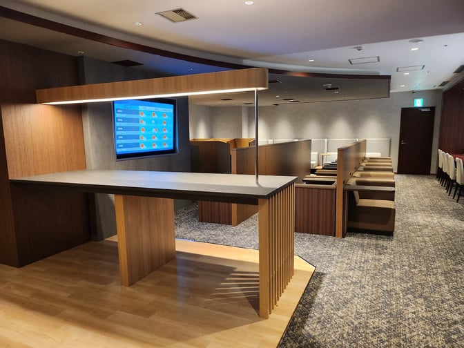 The lounge at Osaka-Itami Airport features booth seating for privacy and a digital display for flight information.
