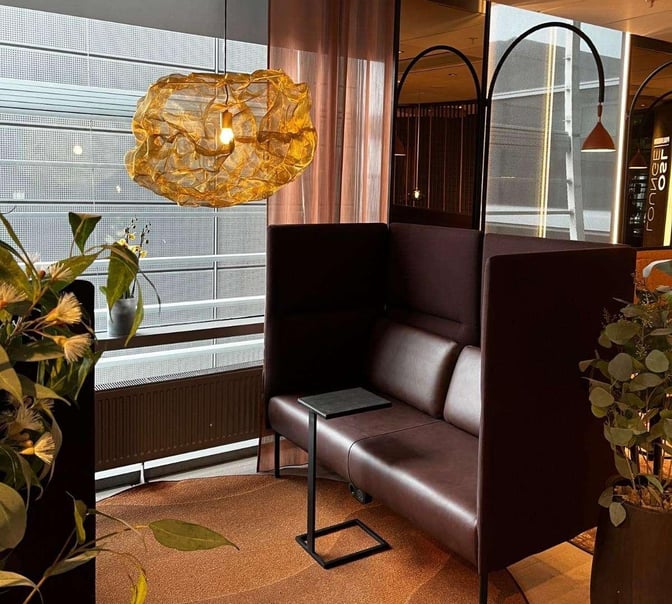 The OSL Lounge at Oslo Airport features a semi-private seating area with high-backed sofas and a small table for travelers.