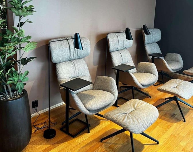 Relaxation chairs with footrests and individual lamps are arranged in a seating area at OSL Lounge International, Oslo Airport.