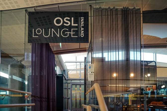 The entrance to the OSL Lounge Innland at Oslo Airport features a sign and glass doors leading into the lounge area.