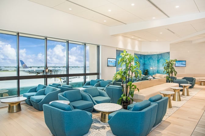 The seating area in the Escape Lounge at Palm Beach International Airport offers comfortable chairs and tables with views of the runway.