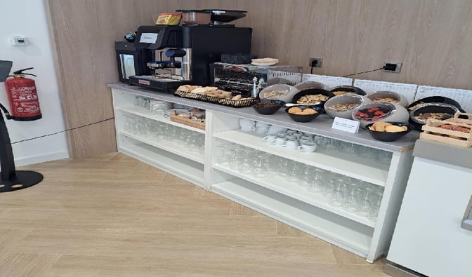 The Mestral VIP Lounge at Palma de Mallorca Airport features a self-serve snack station with pastries, fruits, and a coffee machine.