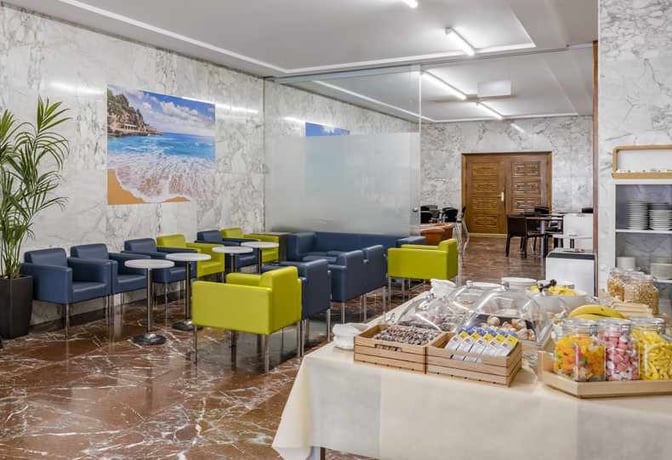 The Sala VIP Llevant at Palma de Mallorca Airport features a seating area with tables and a self-serve snack station.