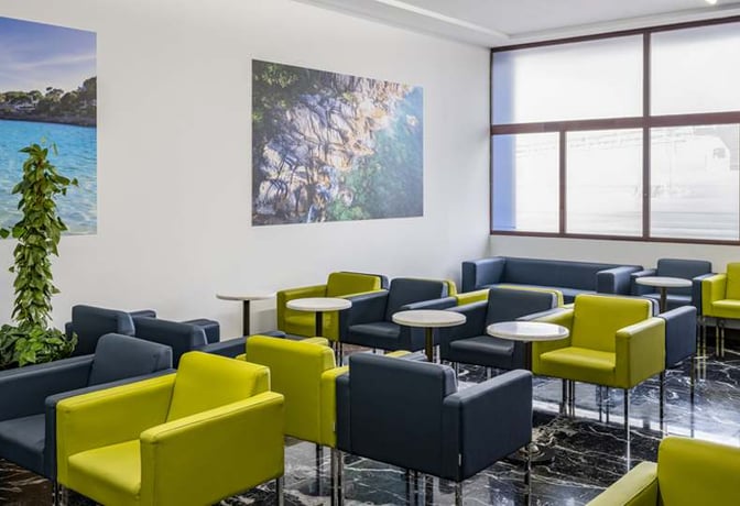 The seating area in the Sala VIP Llevant at Palma de Mallorca Airport features armchairs and small tables for passenger comfort.