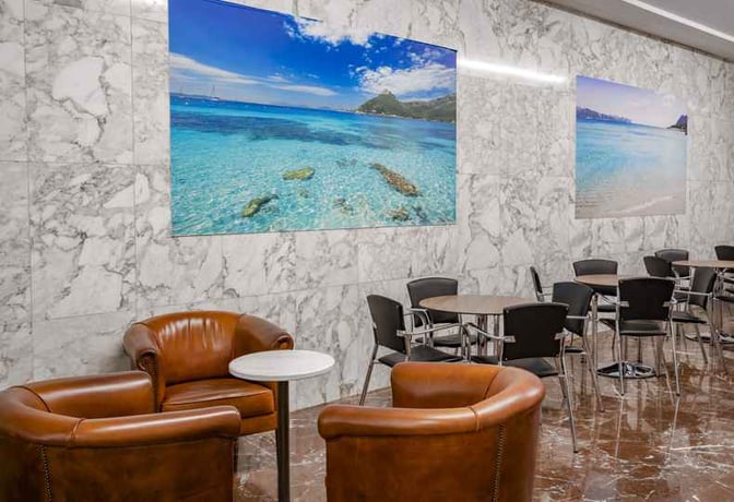 The seating area in Sala VIP Llevant at Palma de Mallorca Airport features leather armchairs and tables with scenic wall art.