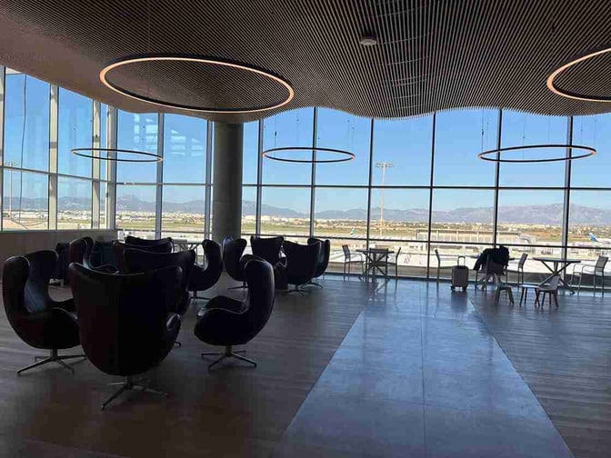 The seating area in the Sala VIP Valldemossa at Palma de Mallorca Airport offers views of the runway through large windows.