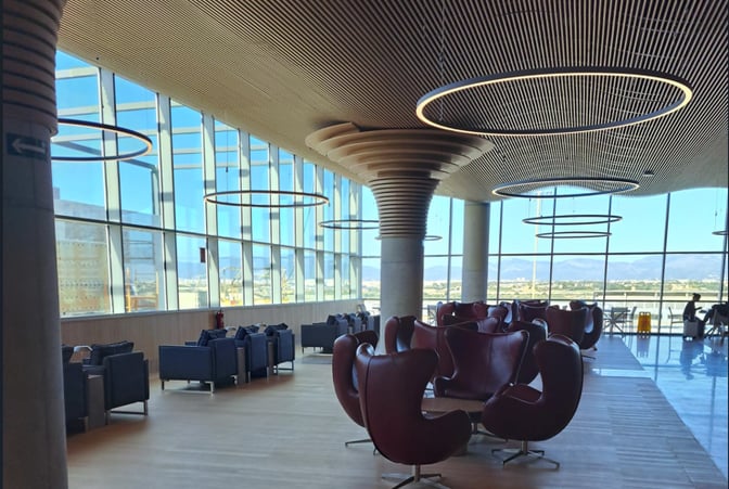 The seating area in Sala VIP Valldemossa at Palma de Mallorca Airport features swivel chairs and couches with expansive window views.