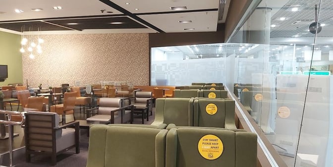 The seating area in Paphos International Airport's Premium Lounge features various chairs and tables with social distancing reminders.