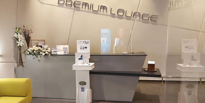 The entrance to the Premium Lounge at Paphos International Airport features a reception desk with informational displays and floral arrangements.