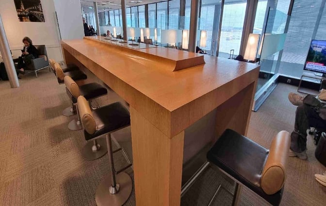 The Salon Paris lounge at Charles de Gaulle Airport features a high-top counter with barstool seating, offering views of the tarmac.