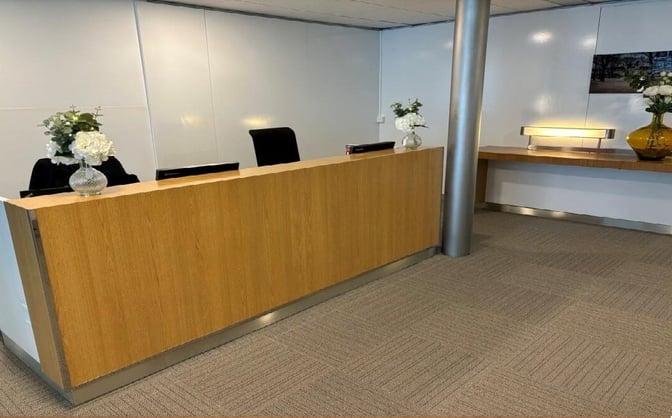 The reception area at Salon Paris in Charles de Gaulle Airport features a wooden desk with floral arrangements and seating for staff.