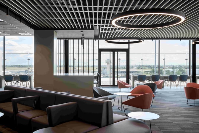 The Primeclass Lounge at Paris-Orly Airport features a seating area with armchairs and tables, offering views of the airport runway.