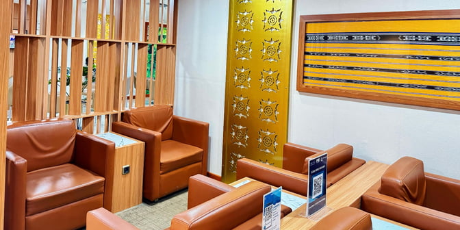 The seating area in Concordia Lounge at Pattimura Airport features comfortable chairs and tables with a decorative partition and wall art.
