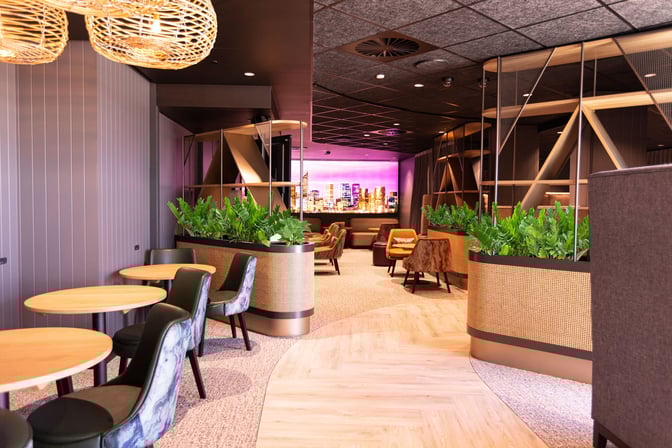 The International Aspire Lounge at Perth Airport features a seating area with round tables, chairs, and partitioned spaces with greenery.