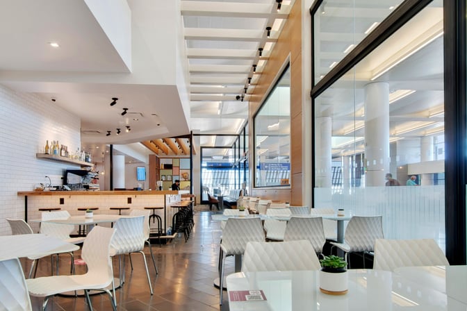 The Escape Lounge at Phoenix Sky Harbor features a dining area with tables and chairs, adjacent to a bar with seating.