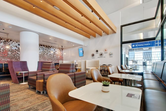 Seating area in the Escape Lounge at Phoenix Sky Harbor offers a mix of chairs and booths with airport views.