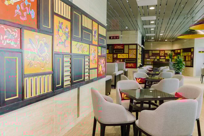 The SH Premium Lounge at Phu Bai International Airport features seating with tables and decorative wall art, providing a comfortable waiting area.