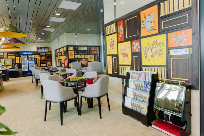 The SH Premium Lounge at Phu Bai International Airport features seating with tables, a beverage fridge, and a magazine rack.