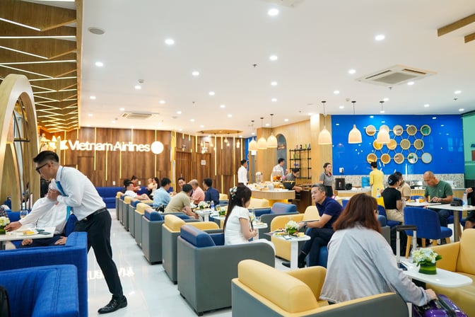The Lotus Lounge at Phu Cat Airport features seating areas with tables for dining and a self-serve food station.