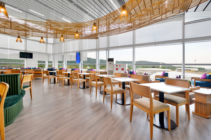 The SH Premium Lounge at Phu Quoc International Airport features spacious seating with tables and large windows offering runway views.
