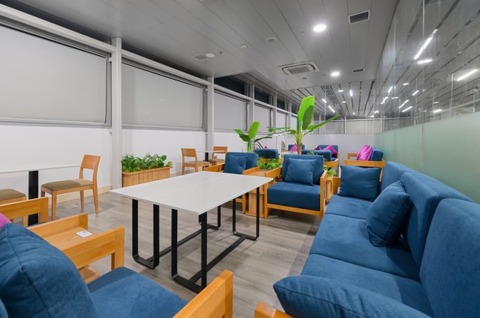 The seating area in SH Premium Lounge Phu Quoc 1 features cushioned chairs and sofas with tables, surrounded by indoor plants.