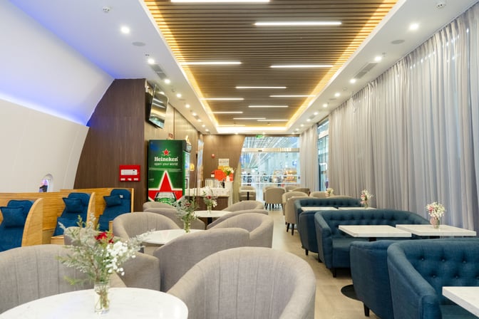 The SH Premium Lounge at Phu Quoc International Airport features comfortable seating with tables, a beverage station, and decorative plants.