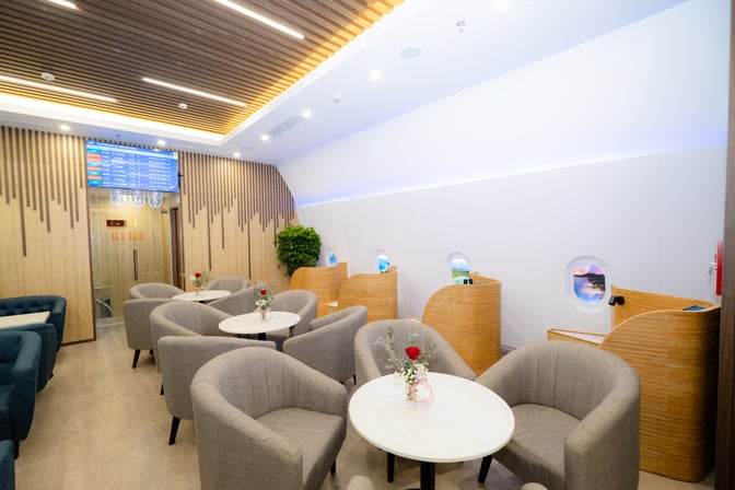 The SH Premium Lounge at Phu Quoc International Airport features seating with tables and semi-private booths resembling airplane windows.