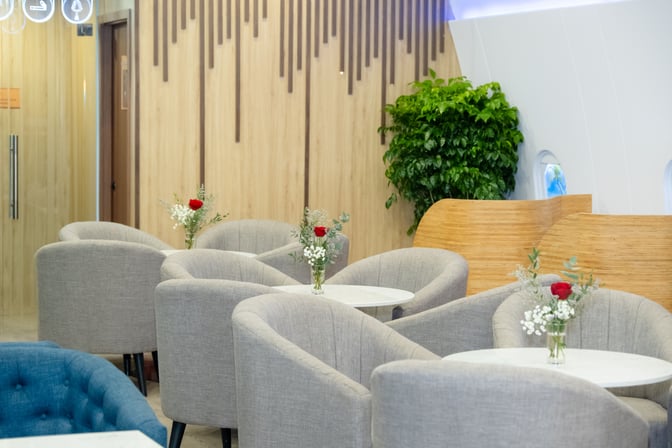 The seating area in SH Premium Lounge Phu Quoc 2 features round tables with comfortable chairs and decorative floral arrangements.