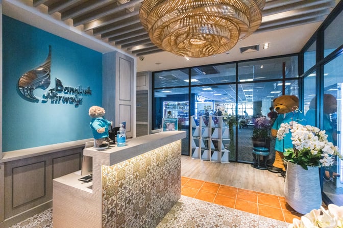 The entrance to Bangkok Airways Blue Ribbon Lounge at Phuket International Airport features a reception desk and decorative elements.