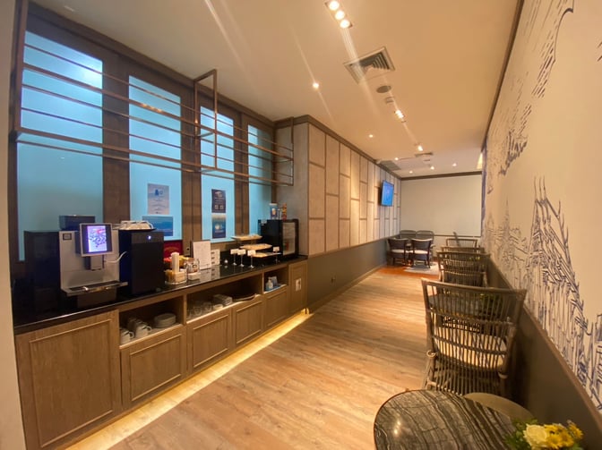 The Bangkok Airways Blue Ribbon Lounge at Phuket International Airport features a self-serve beverage station with coffee machines and seating areas.