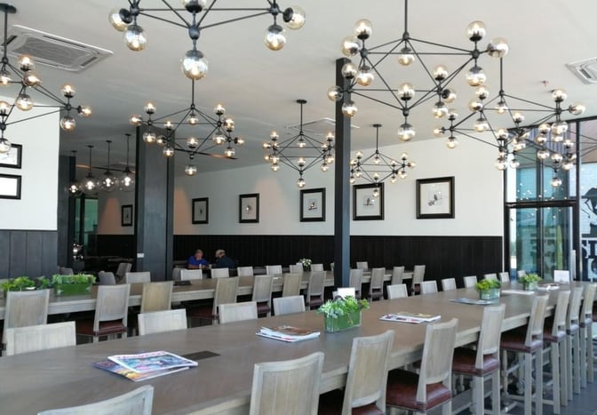 The Coral Premium Departure Lounge at Phuket International Airport features communal tables with seating, offering magazines and decorative plants.