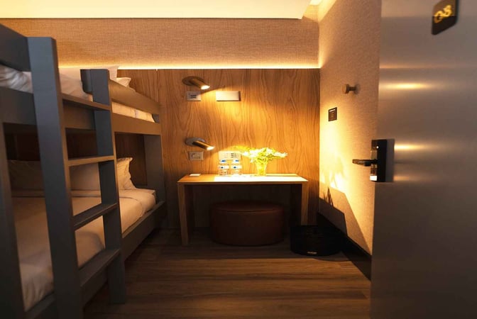 The W Airport Rooms at Fortaleza International Airport feature bunk beds and a small desk with complimentary water bottles.