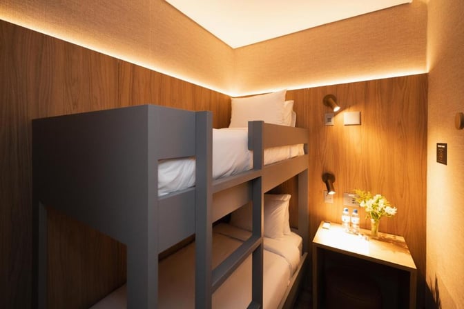 The W Airport Rooms at Fortaleza International Airport feature bunk beds and a small desk with complimentary water bottles.