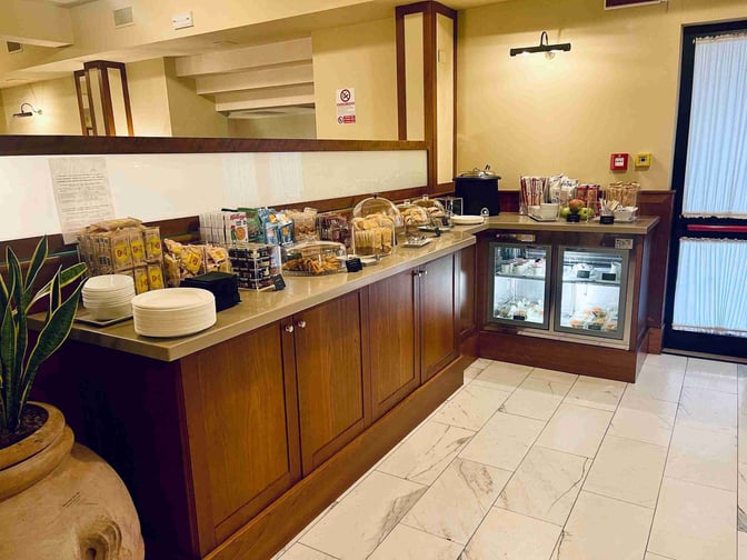 The Galilei VIP Lounge at Pisa International Airport features a self-serve snack station with packaged snacks and refrigerated beverages.