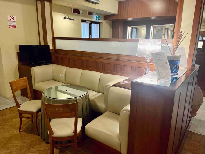 The Galilei VIP Lounge at Pisa International Airport features a seating area with a round table, chairs, and a small TV.