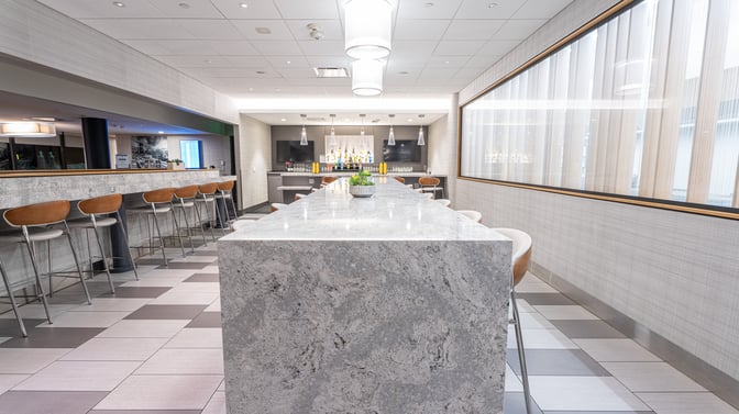 The Club PIT at Pittsburgh International Airport features a bar area with counter seating and a variety of displayed beverages.