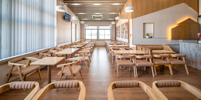 The seating area in SH Premium Lounge Pleiku features rows of tables and chairs, providing ample space for travelers to relax.