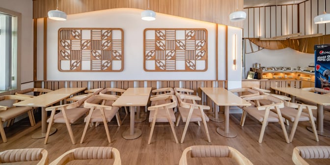 The SH Premium Lounge at Pleiku Airport features a seating area with wooden tables and chairs, adjacent to a self-serve food station.