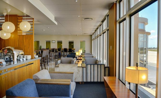 The Bidvest Premier Lounge at Port Elizabeth International Airport features comfortable seating with airport views and a self-serve food station.