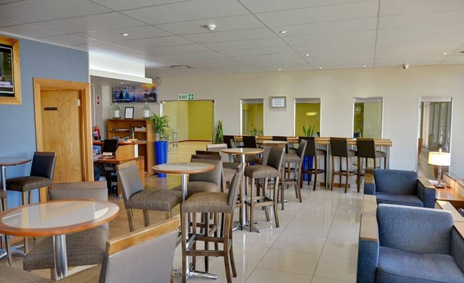 The Bidvest Premier Lounge at Port Elizabeth International Airport features a seating area with tables, chairs, and a reception desk.