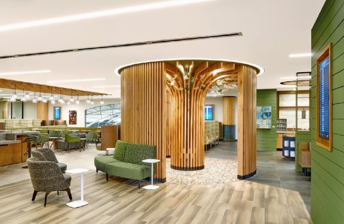 The Escape Lounge at Portland International Airport features diverse seating options, including tables and booths, with a central decorative wooden structure.