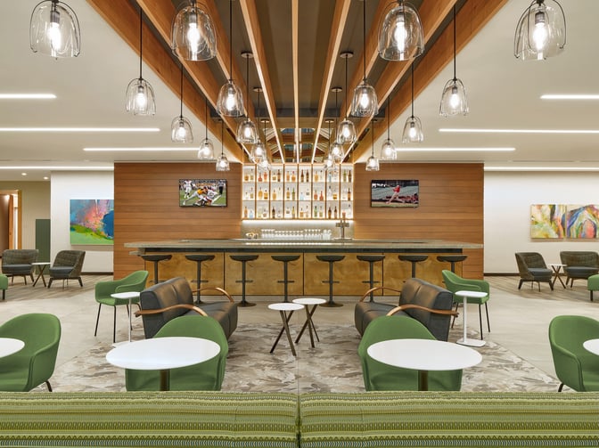 The Escape Lounge at Portland International Airport features a bar with counter seating and a variety of spirits on display.