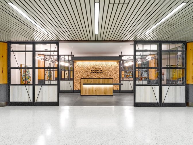 The entrance to the Escape Lounge at Portland International Airport features a reception desk with decorative wood accents.