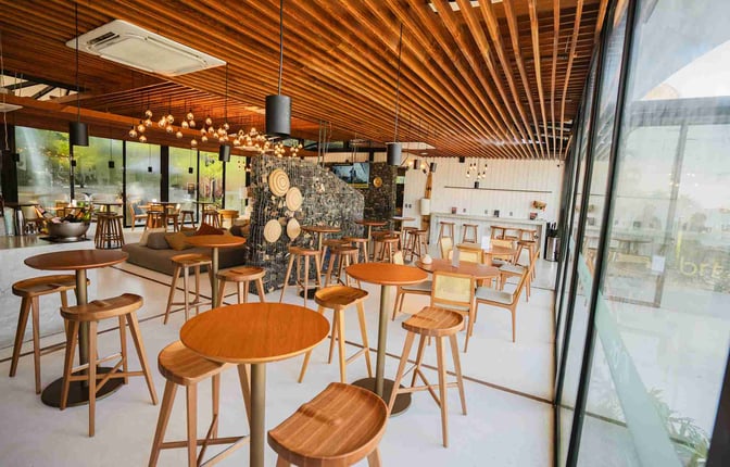 The BRT Lounge at Porto Seguro Airport features a seating area with round tables, high stools, and a bar counter.