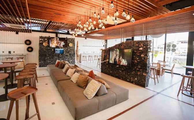 The BRT Lounge at Porto Seguro Airport features a spacious seating area with cushioned sofas, bar stools, and multiple televisions.