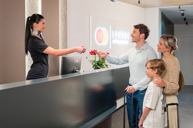 The reception area of the Mastercard Lounge at Prague Vaclav Havel Airport features a check-in desk where guests are greeted.