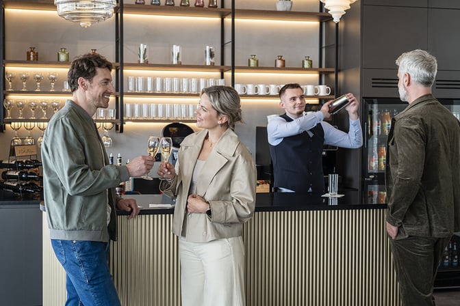 The bar at Mastercard Lounge in Prague Vaclav Havel Airport offers a selection of drinks with a bartender serving guests.