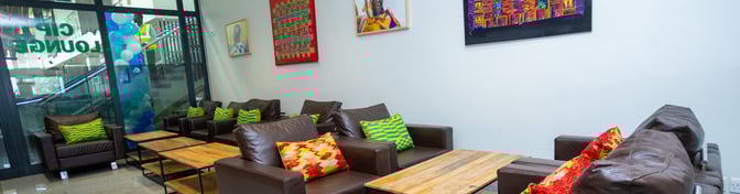The CIP Lounge at Prempeh I International Airport features comfortable seating with wooden tables and decorative artwork on the walls.