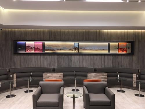 The seating area in the Salones VIP Pacific Club features cushioned chairs and a curved bench with individual tables for travelers.
