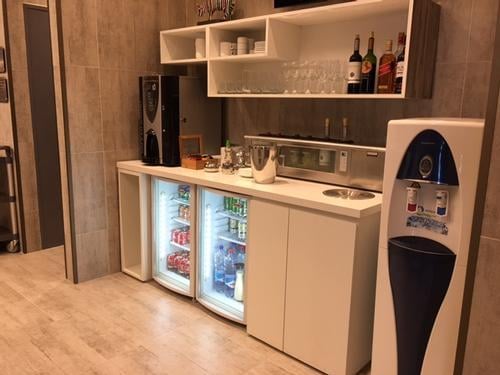 The self-serve beverage station in the Salones VIP Pacific Club offers a selection of drinks, including bottled beverages and coffee.